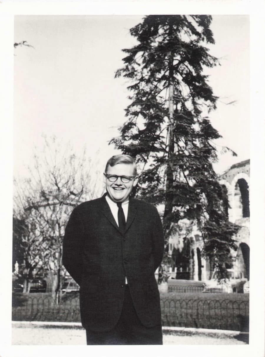 Frank Reynolds as a young man in a suit and glasses