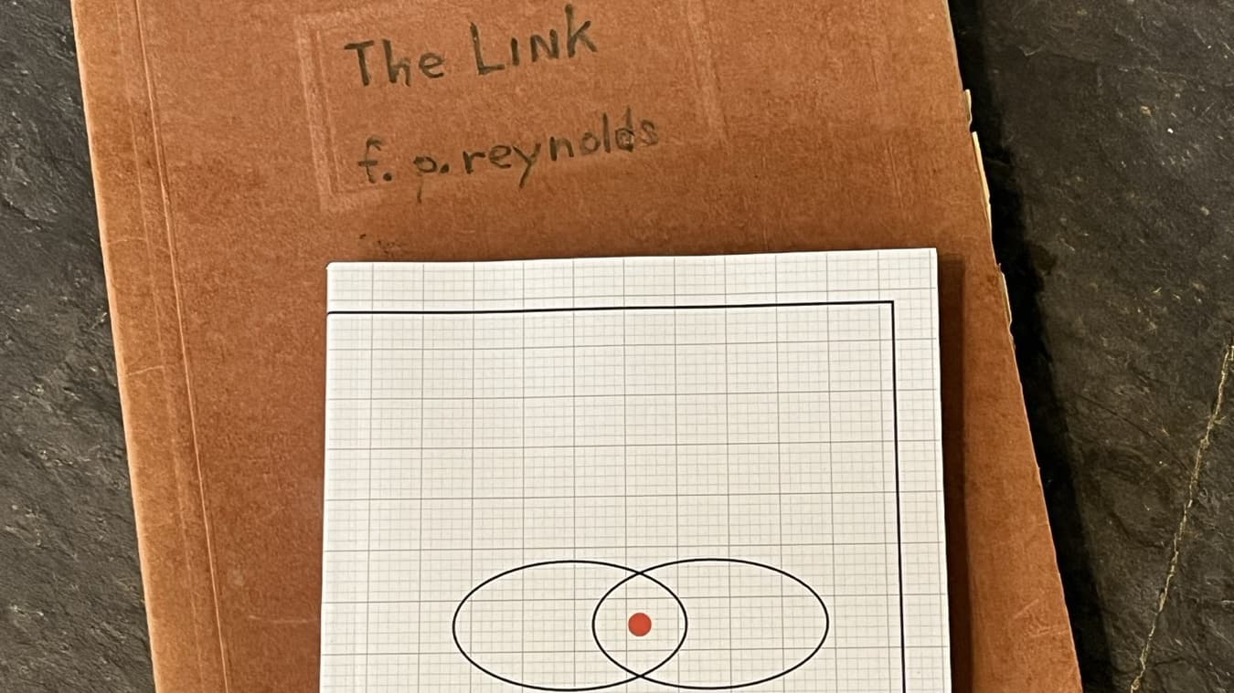 The published paperback of THE LINK resting on the original typescript&rsquo;s red folder, hand-lettered &lsquo;The Link, f. p. reynolds&rsquo;